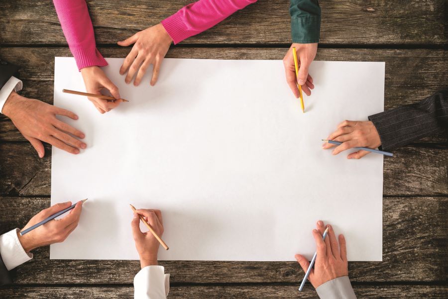 Mains de plusieurs personnes qui dessinent sur la même feuille